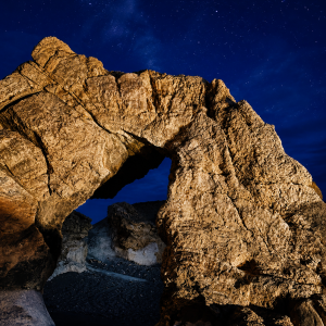 Starlit rock arch in desert night